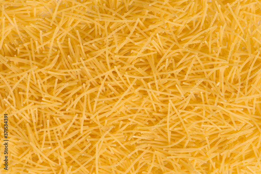 Raw vermicelli pasta background. raw yellow vermicelli is scattered on the table. raw yellow vermicelli scattered randomly on the table. short raw yellow vermicelli for cooking Raw vermicelli pasta background. raw yellow vermicelli is scattered on the table. raw yellow vermicelli scattered randomly on the table. short raw yellow vermicelli for cooking