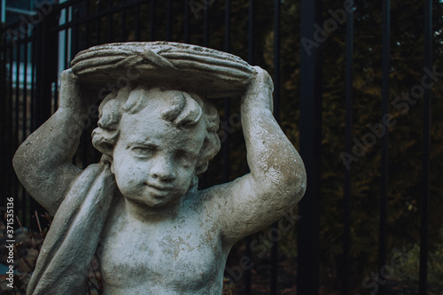 A Small Cherub Statue Holding a Plate Over Its Head