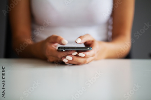 Close up front view young woman holding smartphone, typing message, chatting with friends in social networks.
