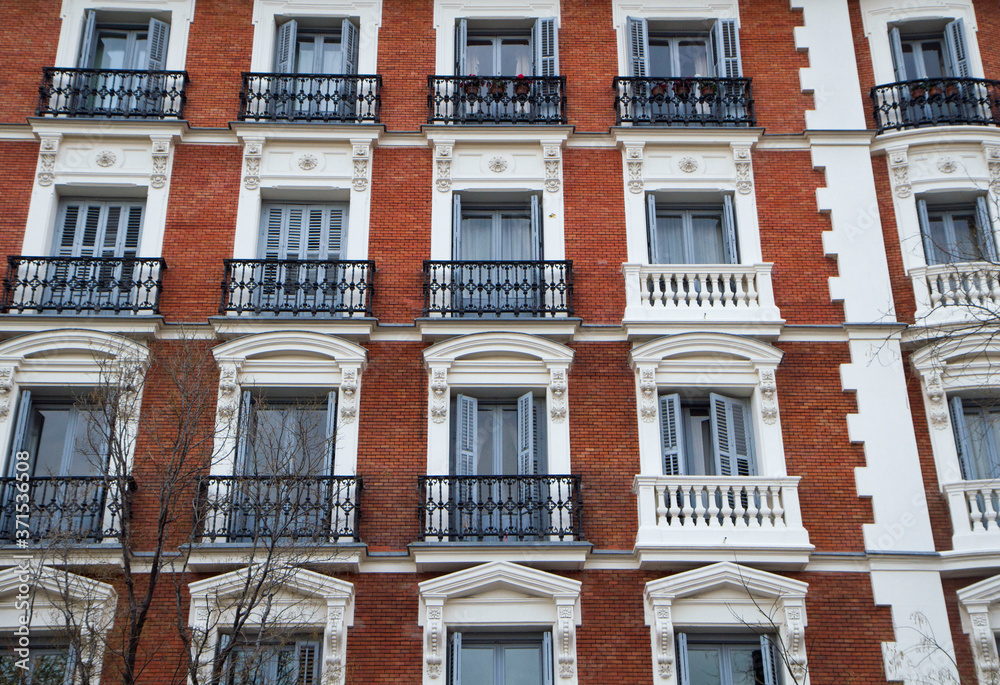 Obraz premium Urban architecture and design. Closeup view of an apartment brick wall facade, windows and french balconies.
