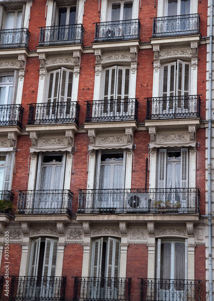 Urban architecture an design. Closeup view of an apartment brick wall facade, windows and french balconies.
