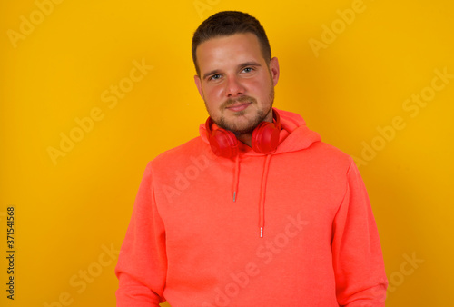 Confidence and business concept. Portrait of charming successful young man, smiling broadly with self-assured expression while holding hands in pockets standing against gray wall.