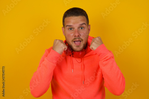 Caucasian young man rejoicing his success and victory clenching his fists with joy.Lucky man with hat being happy to achieve her aim and goals.Positive emotions, feelings.