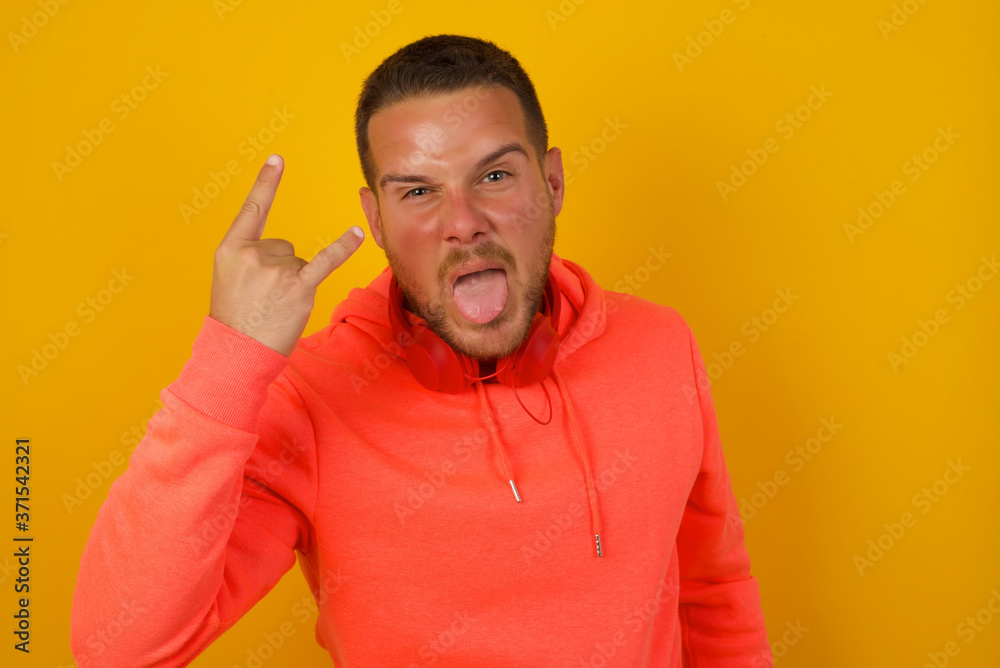 Portrait of a crazy boy showing tongue horns up gesture, expressing excitement of being on concert of band. Portrait of a crazy boy showing tongue horns up gesture, expressing excitement of being on concert of band.