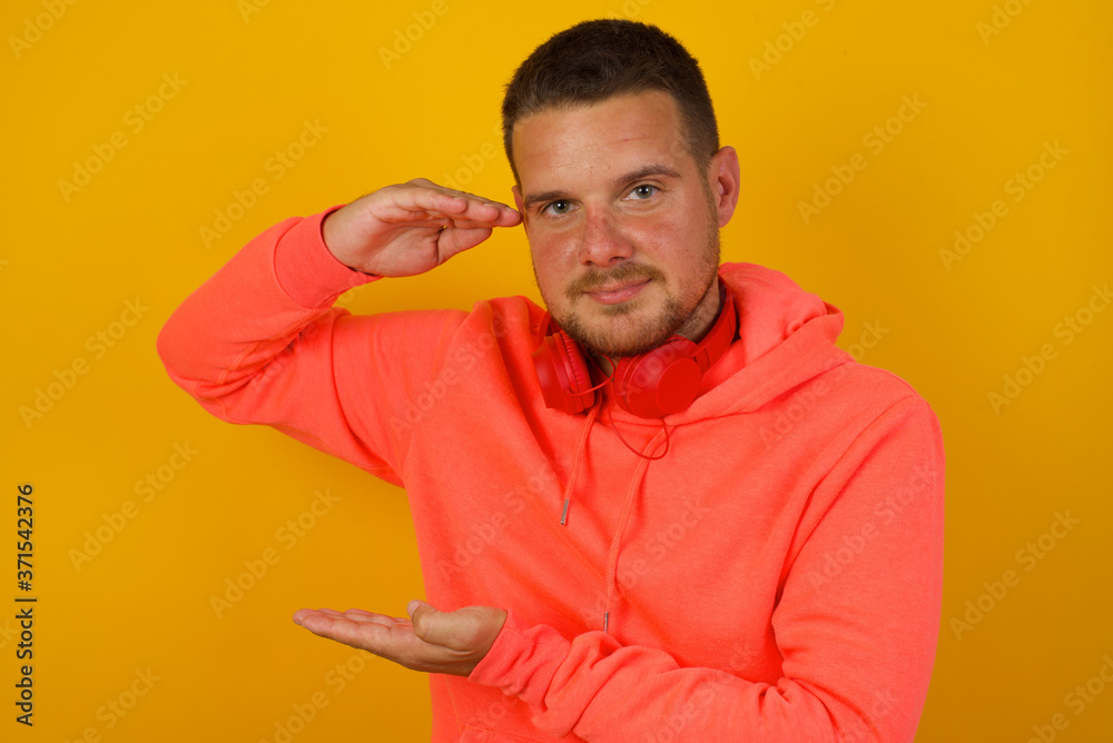 Blond European man over isolated background gesturing with hands showing big and large size sign, measure symbol. Smiling looking at the camera. Measuring concept.