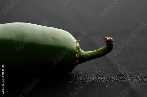 Close up of a jalapeño pepper and placed on a black cloth.