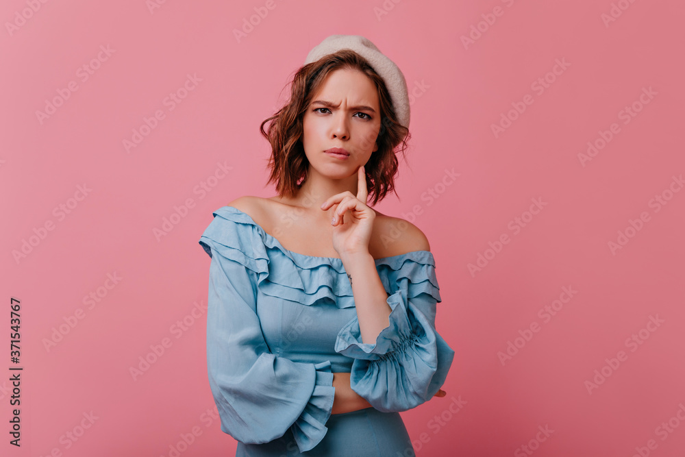 Unpleased white woman in beret looking to camera. Studio shot of unhappy french lady in blue dress isolated on pastel background. Unpleased white woman in beret looking to camera. Studio shot of unhappy french lady in blue dress isolated on pastel background.