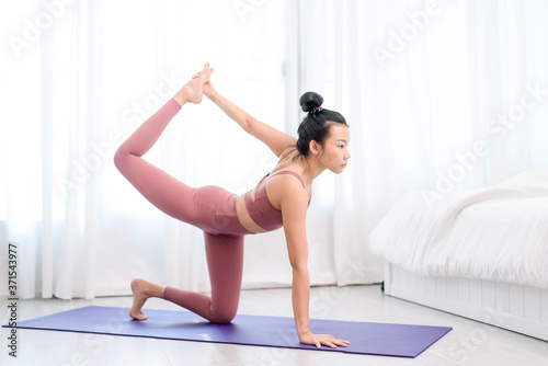 Young woman do yoga in a bed room