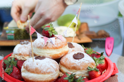 Strawberry tops a pile of chocolate filled donuts - outdoor picnic with bunting