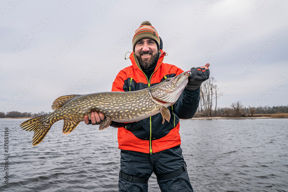 Success pike fishing. Happy fisherman with big fish trophy at boat Success pike fishing. Happy fisherman with big fish trophy at boat
