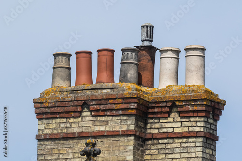 Different styles of chimney pots in double stack against blue sky photo