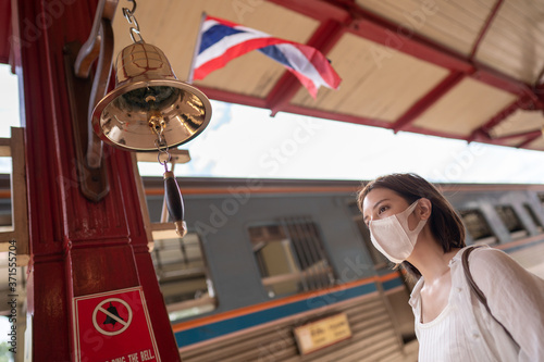 Woman in protective mask wait for the local train on platform at station.