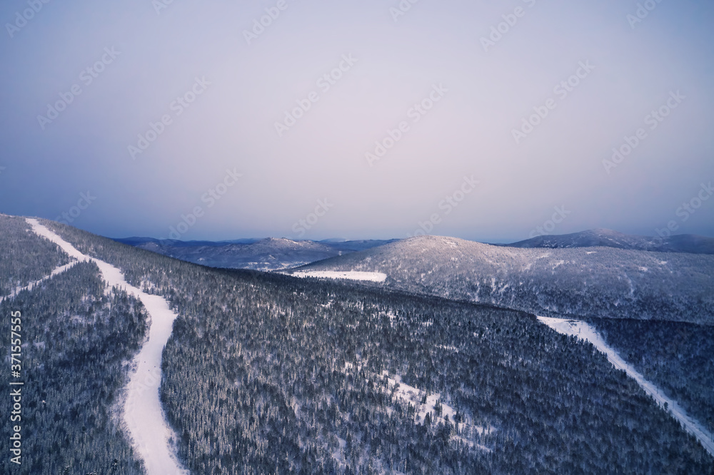 Sunset above Winter landscape aerial view, snow covered pine tree forest mountains