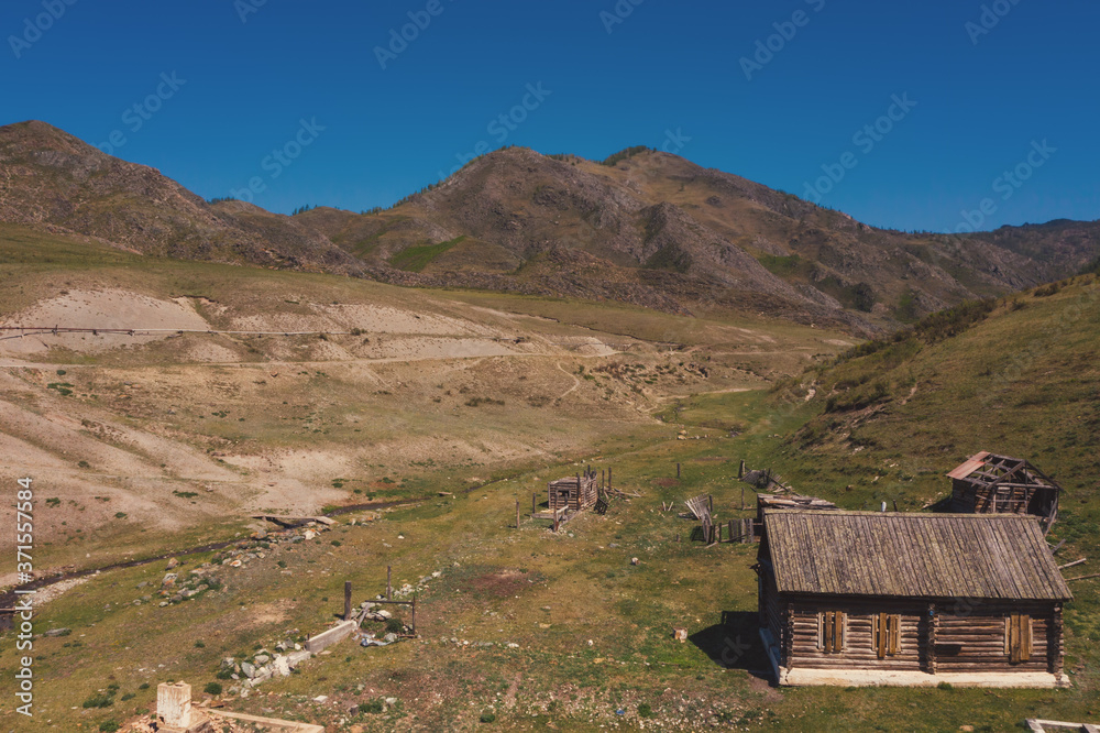 Aerial view on old abandoned wooden house in beautiful mountains valley, summer landscape