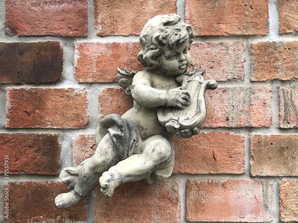 A statue of a little angel playing the beautiful harp of the wall