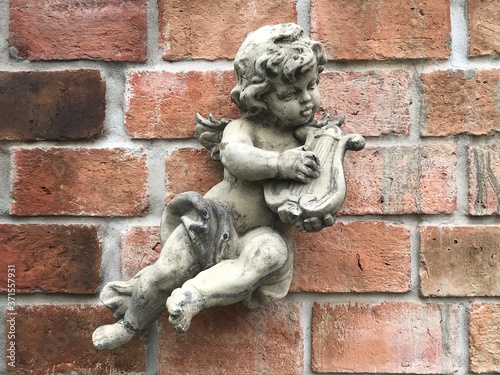 A statue of a little angel playing the beautiful harp of the wall