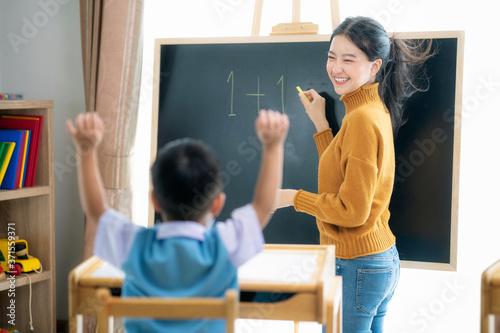 Foto Asian woman teacher and her smart student in class room with backboard backgroun