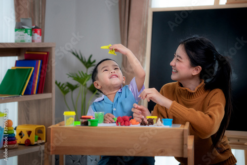 Asian kid and his teacher play doh togather in class room in preschool photo