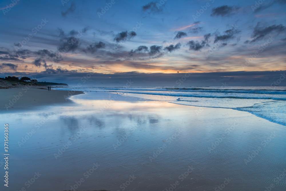 Sunrise seascape with cloud reflections on the beach