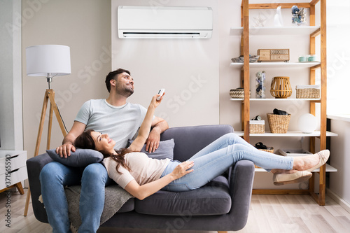 Happy Woman Holding Air Conditioner Remote photo