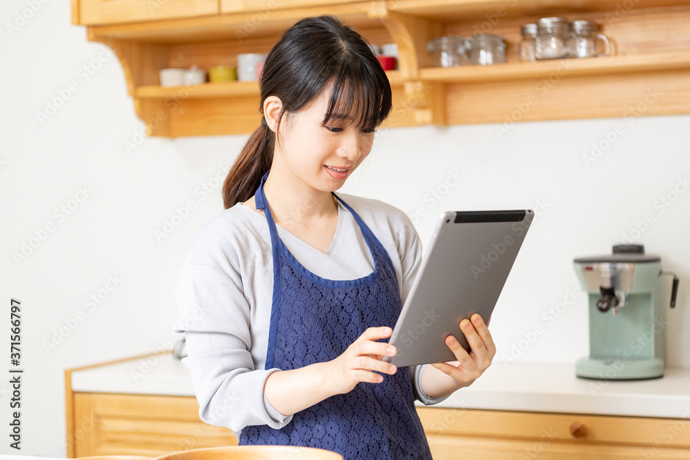 キッチンでタブレットを使う若い女性