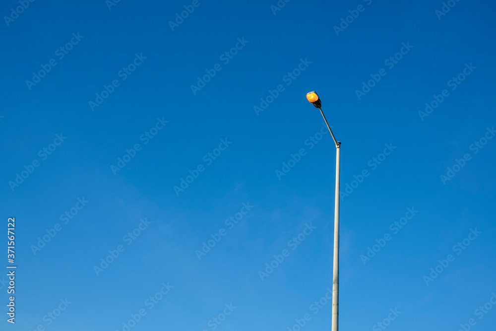 switched on street light against a clear blue sky