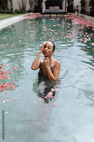Fototapeta Naklejka Na Ścianę i Meble -  Beautiful female in swimming pool background with red Spa flowers