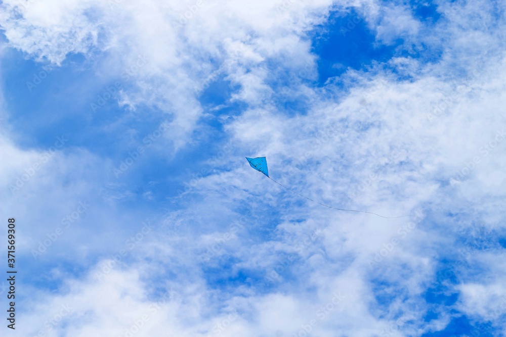 A blue kite flying against a blue sky. Kite flying in the sky among the clouds. Chandpur, Bangladesh / 2020. A blue kite flying against a blue sky. Kite flying in the sky among the clouds. Chandpur, Bangladesh / 2020.