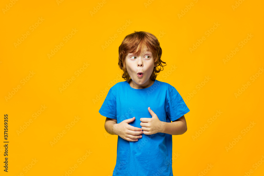 red-haired child surprise blue t-shirt yellow background childhood red-haired child surprise blue t-shirt yellow background childhood