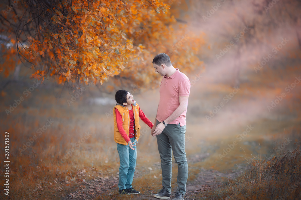 Man with boy in the autumn forest. Son and father. Happy family. Autumn family portrait. Autumn holidays.