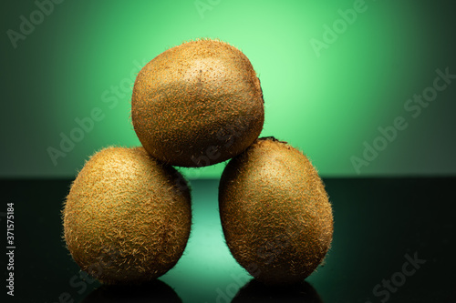 several kiwis on dark glass with green glare on green background