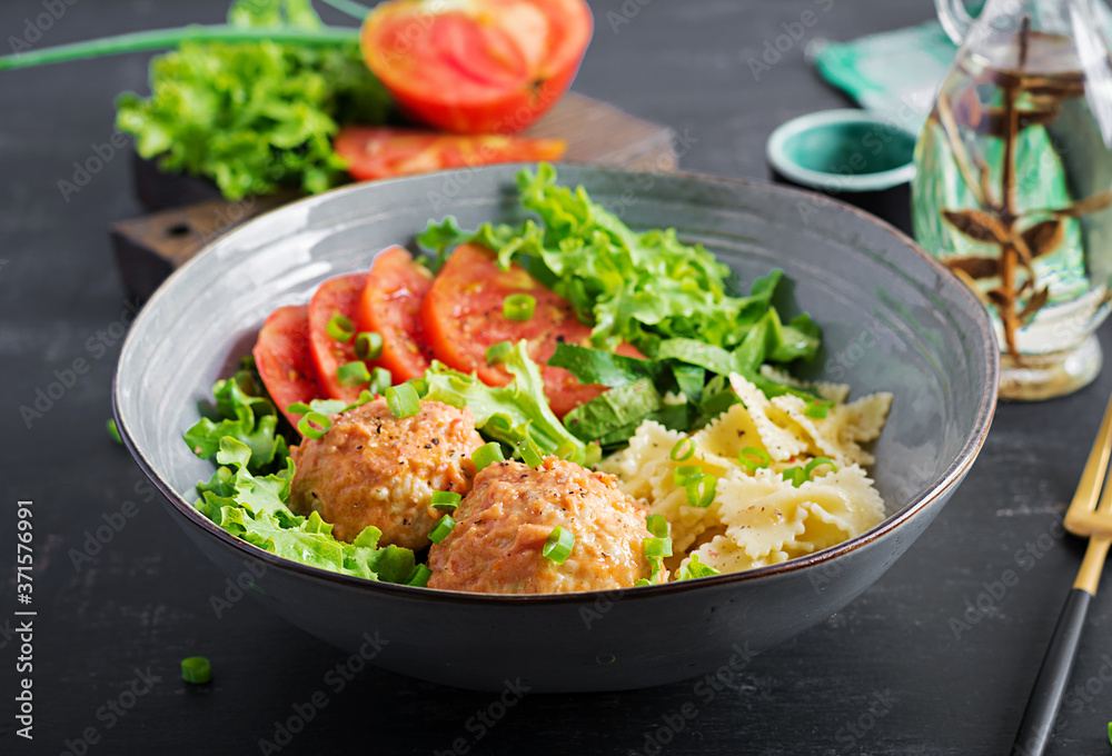 Italian pasta. Farfalle with meatballs and salad on dark background. Dinner. Slow food concept Italian pasta. Farfalle with meatballs and salad on dark background. Dinner. Slow food concept
