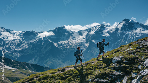 Two young hikers walking up a mountain in Austria, with scenic views on the background