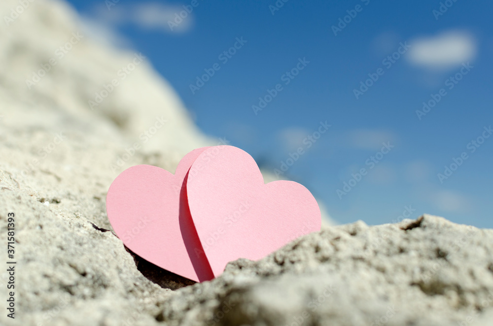 Closeup of two pink heart shape on the rocks against summer sunny sky Closeup of two pink heart shape on the rocks against summer sunny sky