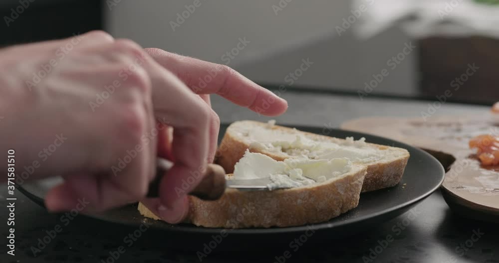 Slow motion man spread cream cheese on ciabatta slice on black plate Slow motion man spread cream cheese on ciabatta slice on black plate