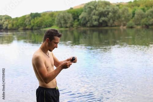 A white Caucasian young man or adult guy with an action camera is filming on the river. photo