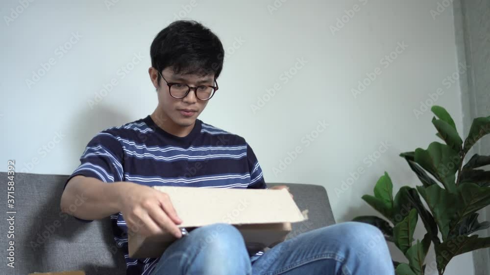 close up young asian man unboxing on package to checking about stuff from online shopping shipment at home for social distance and logistic business concept close up young asian man unboxing on package to checking about stuff from online shopping shipment at home for social distance and logistic business concept