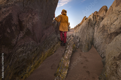 Rock formations on Båtsfjord coastline with woman in yellow jacket