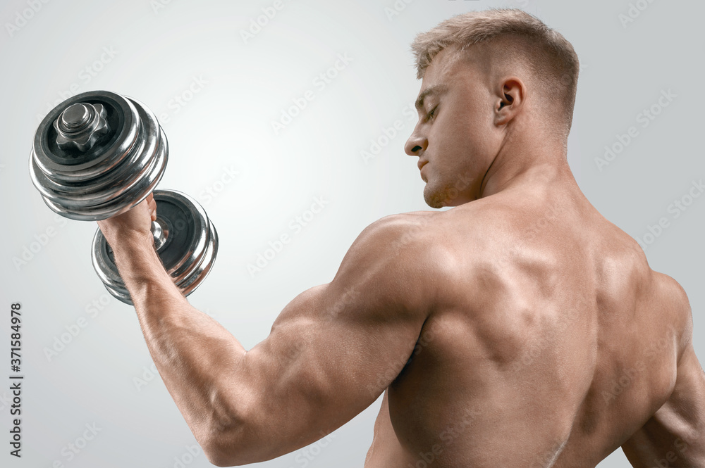 Closeup of a handsome power athletic man bodybuilder doing exercises with dumbbell. Fitness muscular body on dark background. Closeup of a handsome power athletic man bodybuilder doing exercises with dumbbell. Fitness muscular body on dark background.