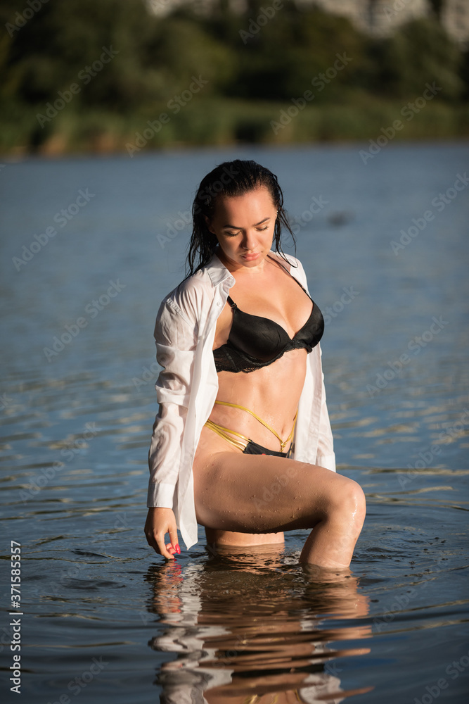 Young European woman with dark hair in wet closes posing in water Young European woman with dark hair in wet closes posing in water