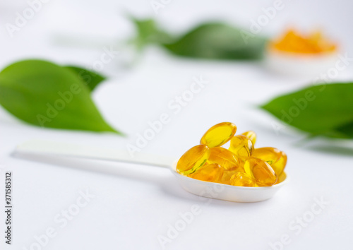 Capsules of vitamin A and E, Golden fish oil in a spoon. Nutritional supplements for good health on a white background. Supplementary feeding. Omega-3. Concept of health and healthy nutrition