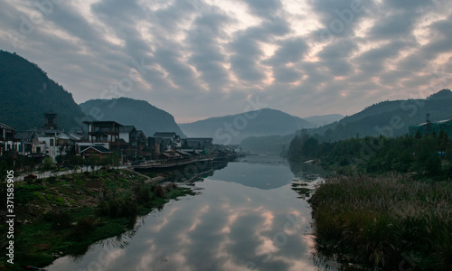 The sunrise scenery of Xibu Street in Zhangjiajie, Hunan province is composed of stilted buildings, ancient buildings, streets, rivers, orange sky and reflection as the background, and quiet effect. C photo