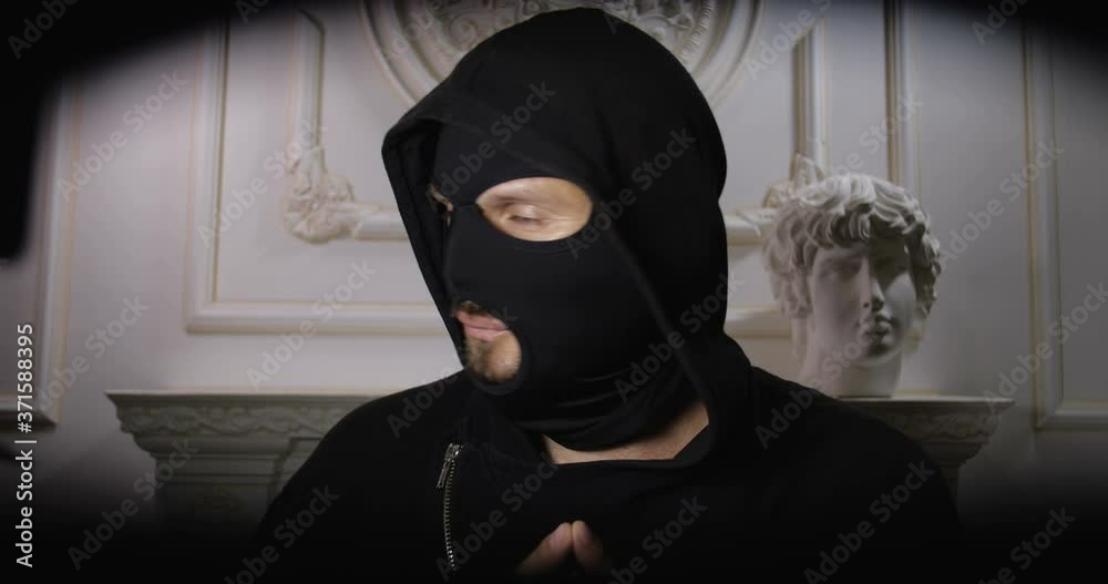 Robbery of the museum. A man in black clothes and balaclava closing the bag zipper. Point of view from the bag where funny robber is putting his loot. Security system concept. Robbery of the museum. A man in black clothes and balaclava closing the bag zipper. Point of view from the bag where funny robber is putting his loot. Security system concept.