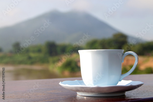 white Cup of coffee on moutain background in the morning near the river.