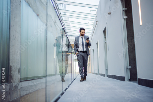Young attractive businessman walking around building in construction process and reading an e-mail fromm important client. photo