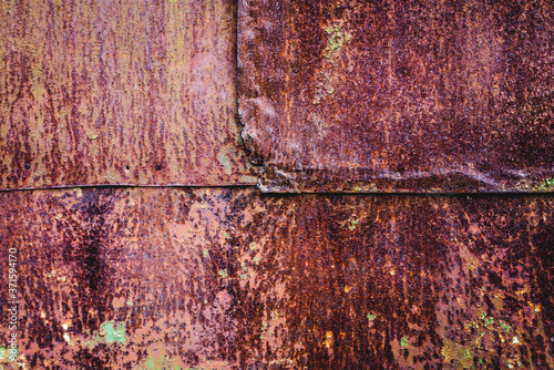 The old iron background is painted yellow, orange, purple, red in with rust and chips