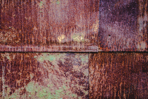 The old iron background is painted yellow, orange, purple, red in with rust and chips