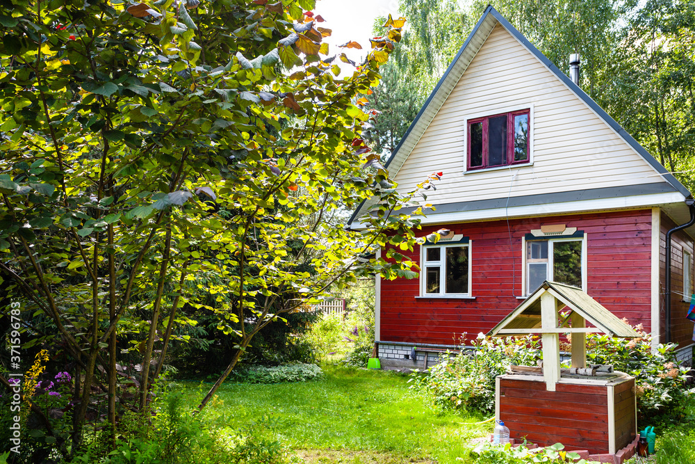 view of small wooden country house and well on backyard in Russia on sunny summer day