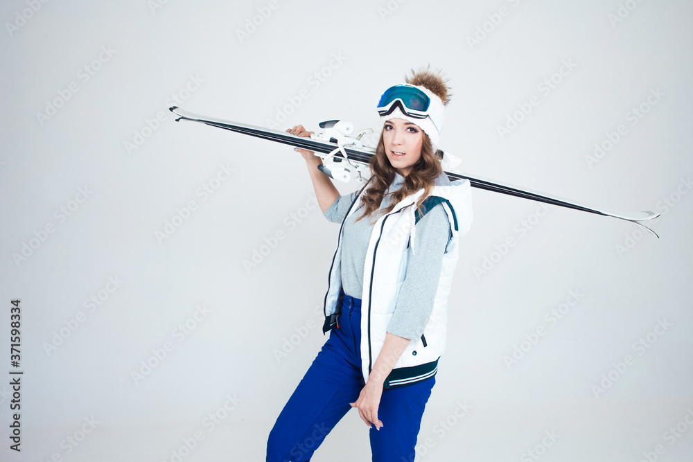 Smiling girl skier in a hat and mask for skiing. A young woman in clothes for skiing and outdoor activities.