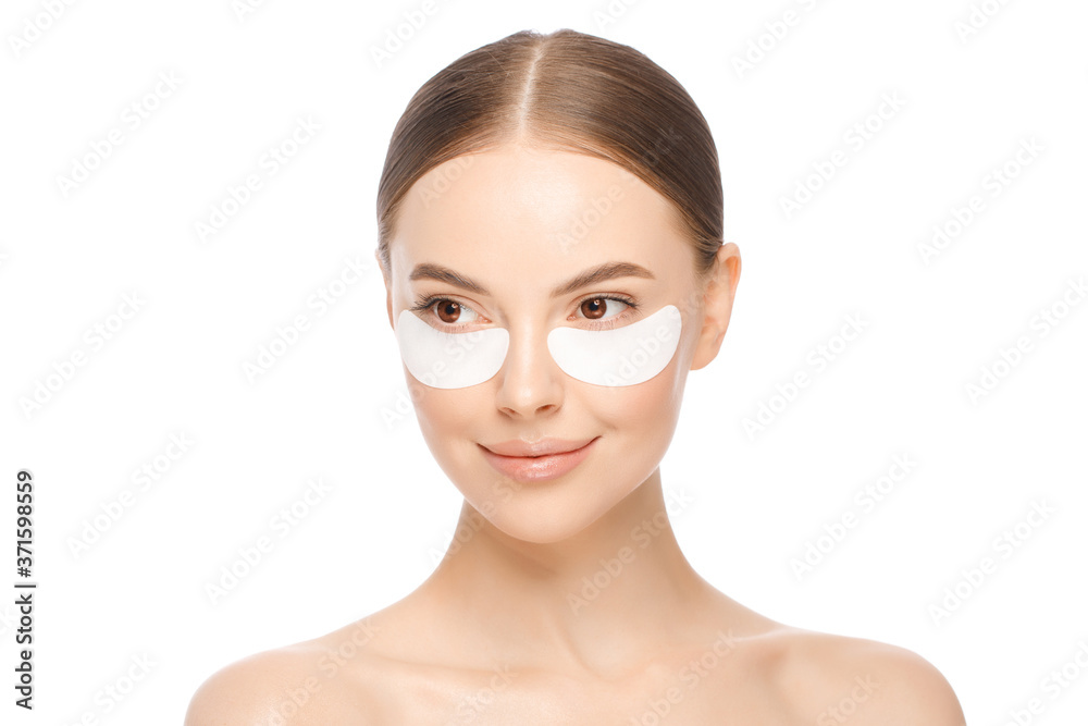 Close-up portrait of young beautiful brown-eyed woman wearing eyepatches to look fresher, looking aside, isolated on white background. Female beauty concept Close-up portrait of young beautiful brown-eyed woman wearing eyepatches to look fresher, looking aside, isolated on white background. Female beauty concept
